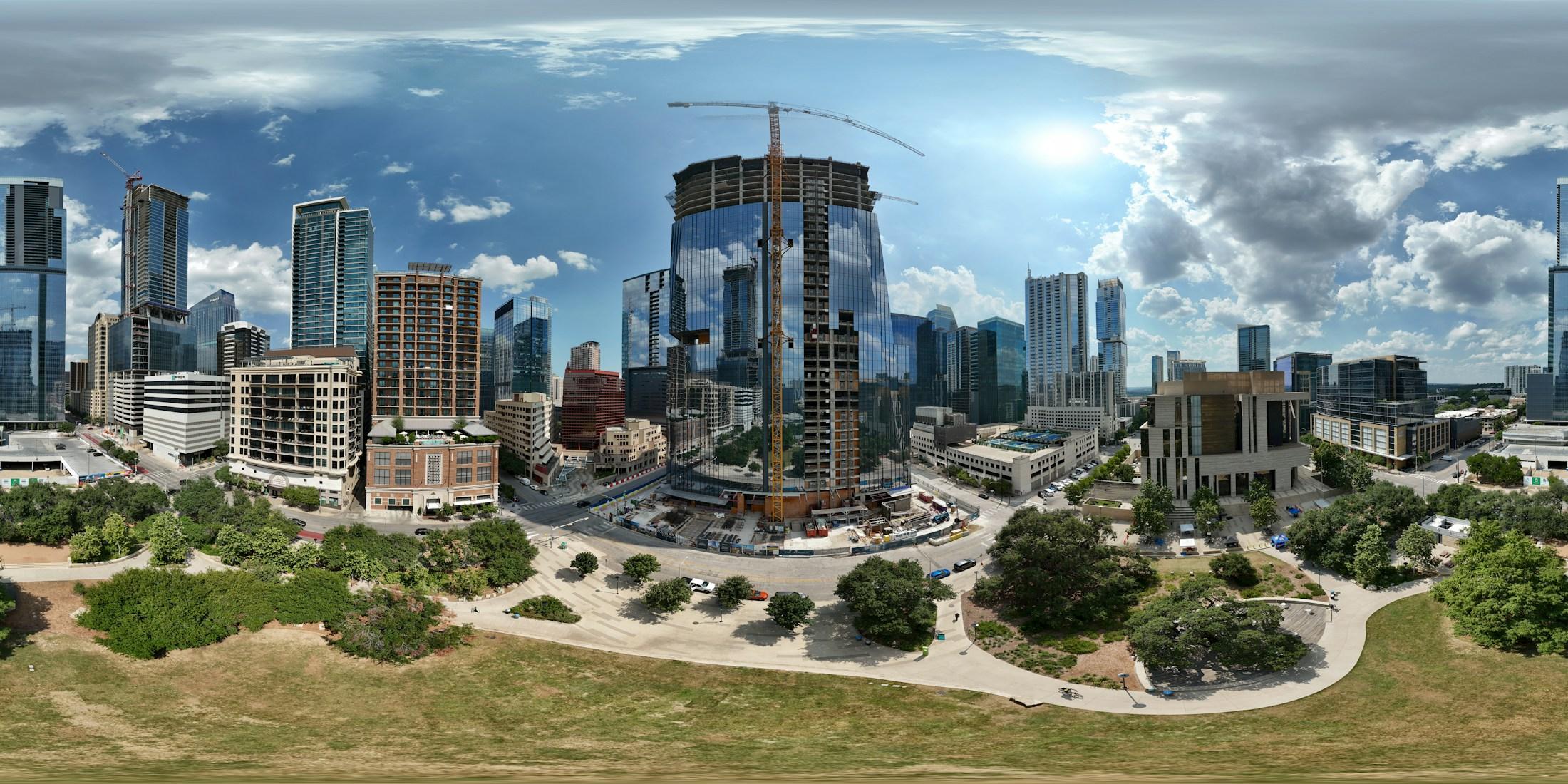 Panoramic city skyline centered on a glass tower under construction